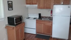 A compact kitchen with wooden cabinets, a microwave, stove, sink, and a refrigerator. - Cozy 1 BR efficiency apt close to TTU and downtown (Cookeville)