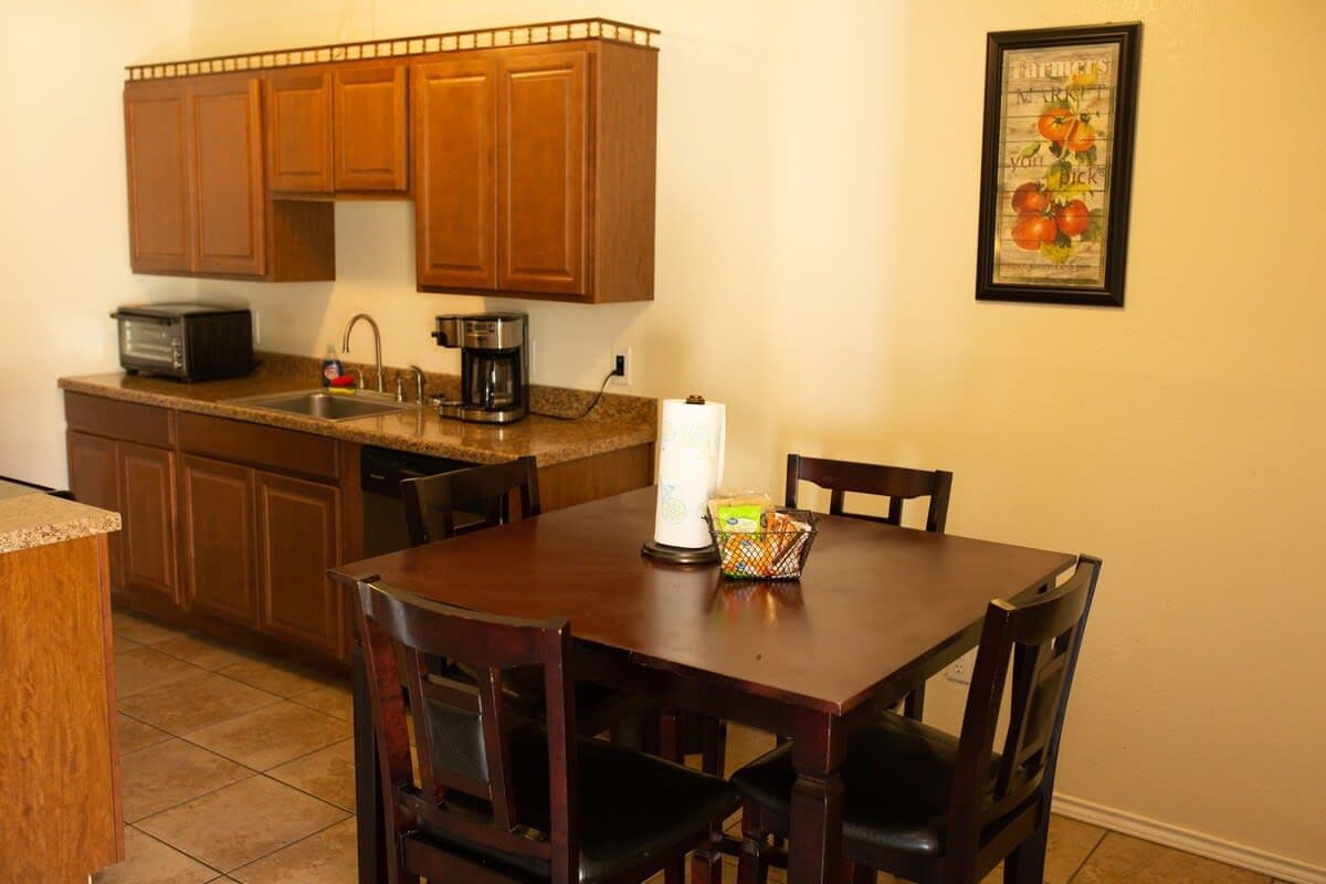 A kitchen with wooden cabinets, a coffee maker, a toaster, and a framed picture on the wall.