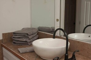 Bathroom features a large sink, mirror, and towels.