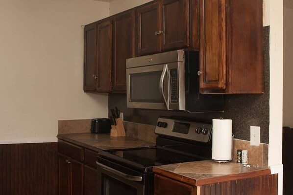 Kitchen area features a stovetop with four burners, microwave oven, and ample counter space.