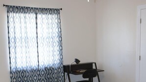 Un dormitorio con cama, escritorio y ventilador de techo.