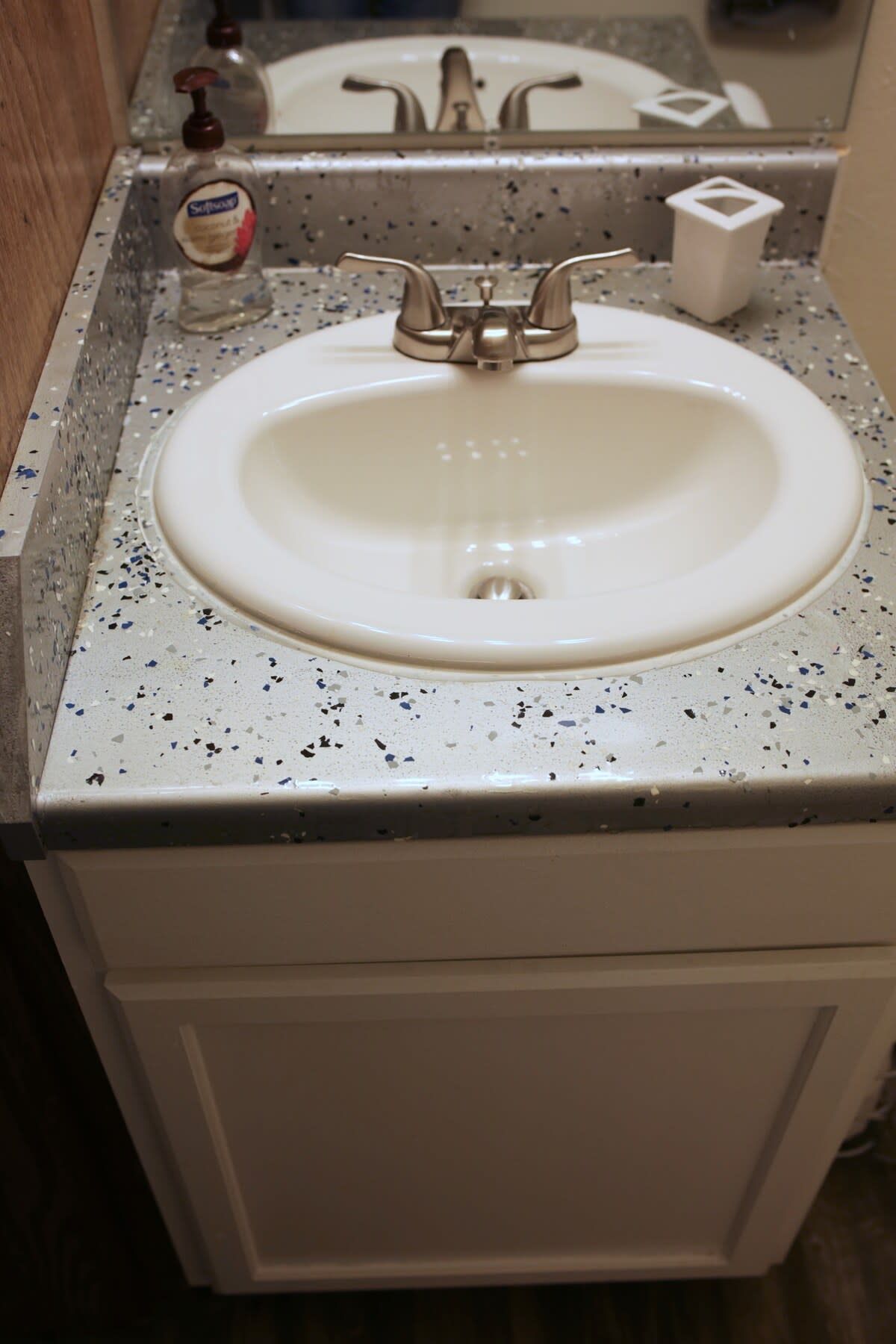 Un lavabo de salle de bain avec un plan de toilette à motifs et un miroir au-dessus.