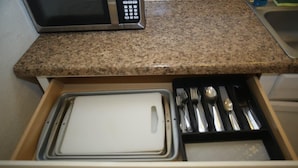 Un tiroir de cuisine contenant un micro-ondes, des ustensiles et une planche à découper.