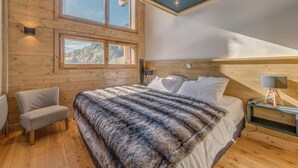 Une chambre à coucher avec un grand lit, une chaise et une table de chevet avec une lampe.