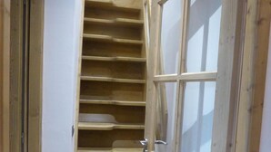 Un escalier en bois mène à une porte dotée d’un panneau en verre dépoli.