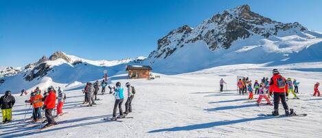 A ski resort with a lodge, skiers, and a mountain backdrop.