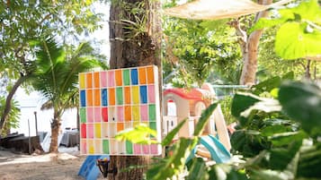 A beach area with a colorful board game, a small playhouse, and a palm tree.