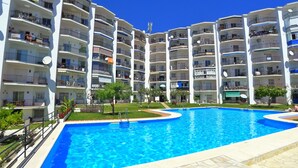 A multi-story residential building with a central swimming pool surrounded by balconies. - 2 Bedrooms | Edf Almijara | CG R679 (Nerja)