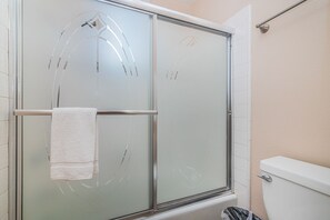 A glass-enclosed shower stall with a towel hanging on the door handle.