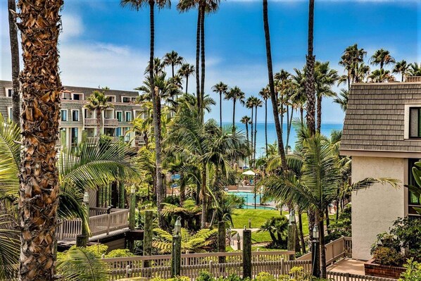 A resort with a pool, palm trees, and a view of the ocean.