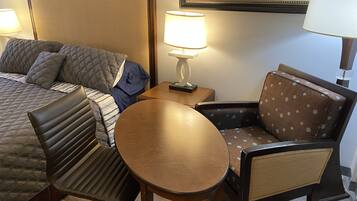 Una habitación de hotel con cama, escritorio, silla y lámpara.