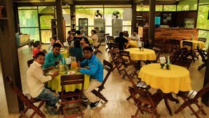 Ein Restaurant mit Holztischen und -stühlen, großen Fenstern und einer Bar.