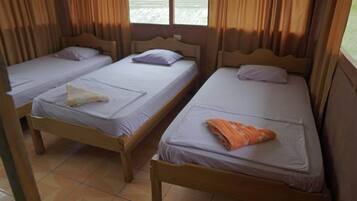 Una habitación con dos camas de madera, cada una con una almohada y una toalla doblada.