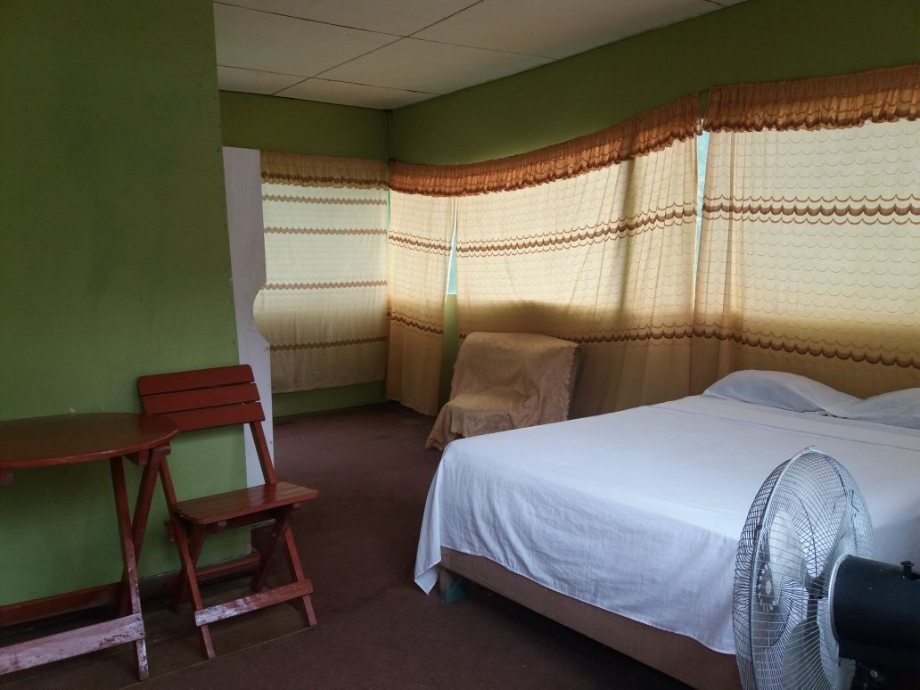 Una habitación con cama, una silla, una mesa y un ventilador.
