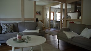 Uma sala de estar com dois sofás, uma mesa de centro e uma área de jantar com mesa e cadeiras.