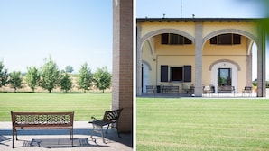 A courtyard with a bench, a table, and chairs under an arched roof. - Agriturismo Il Mondo (Parma)