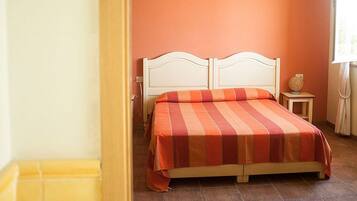 A bedroom with a bed, a nightstand, and a window.