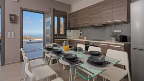 Una cocina moderna con una mesa de comedor de vidrio, sillas blancas y armarios de madera.