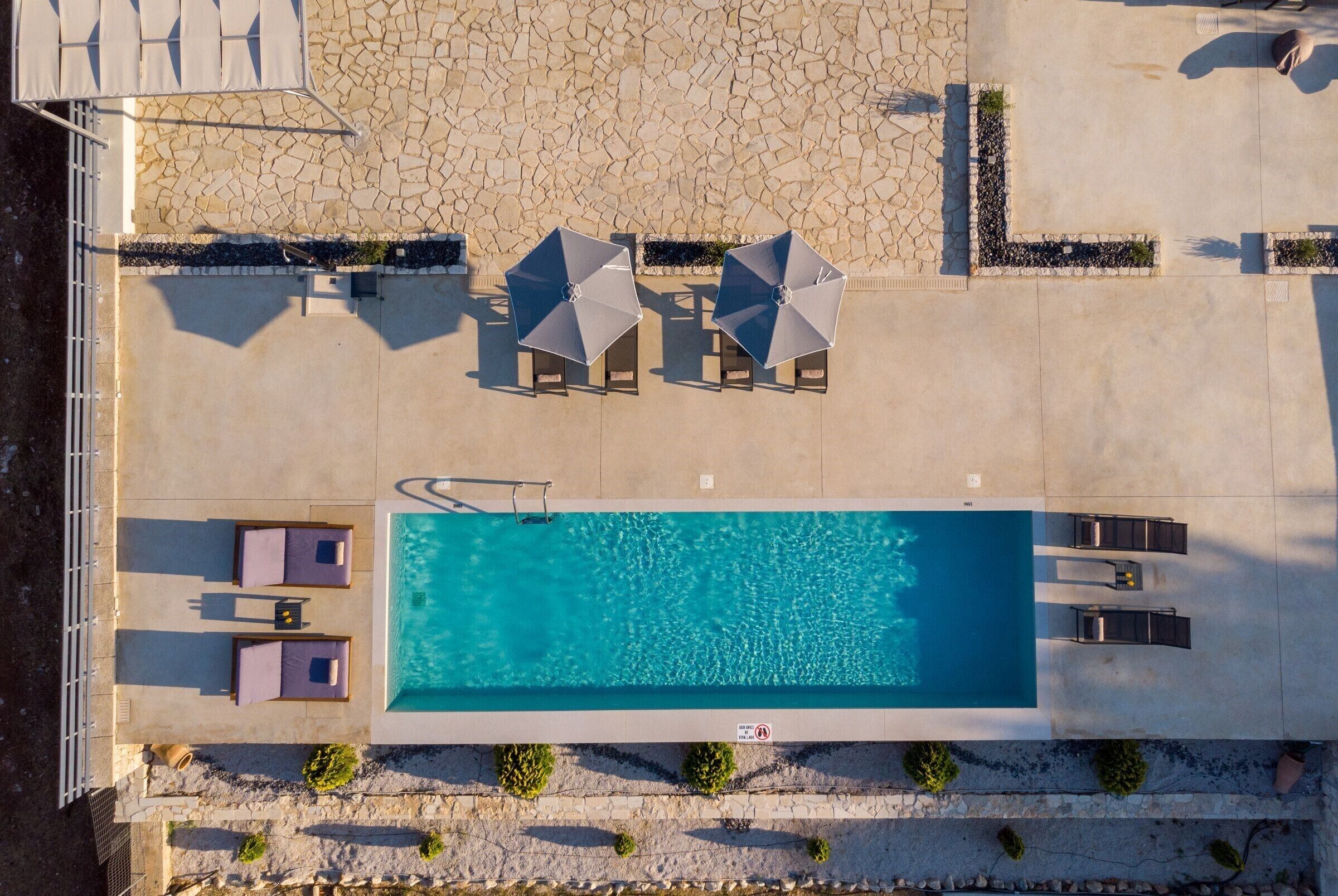 An aerial view of a swimming pool area with lounge chairs and umbrellas.
