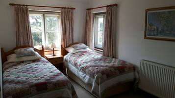 Ein Zimmer mit zwei Einzelbetten, einem Nachttisch mit Lampe und einem Heizkörper.