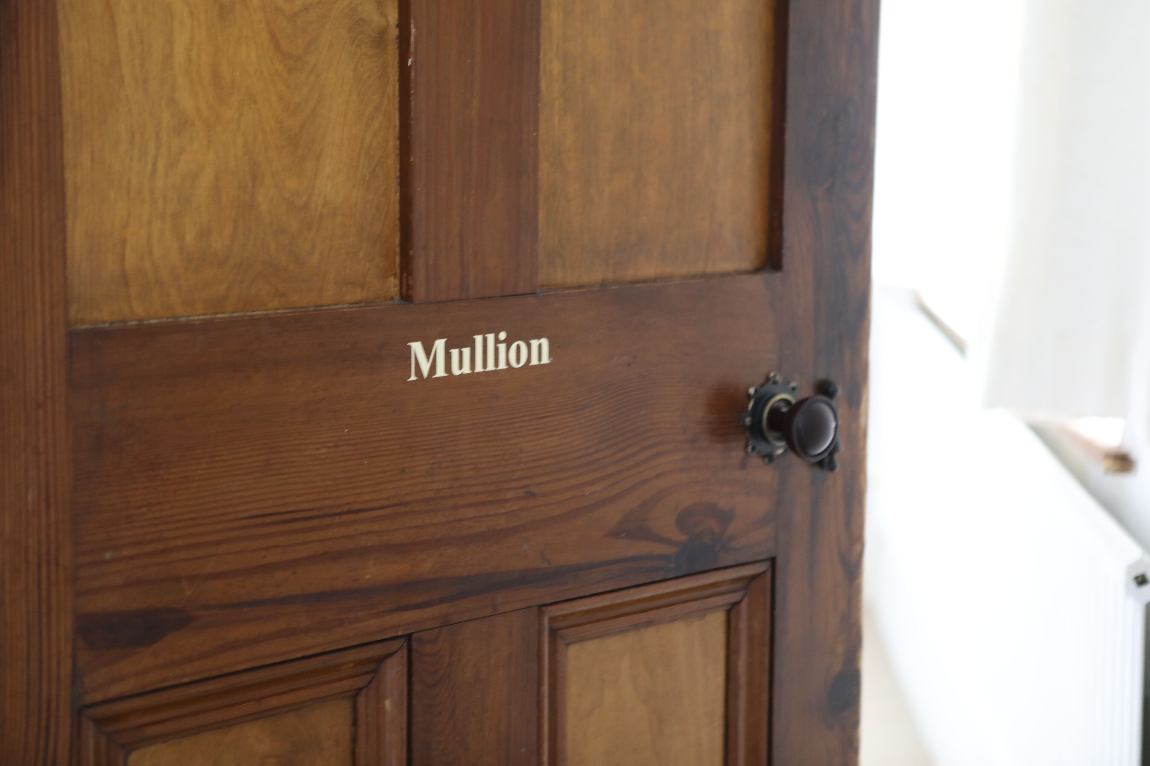 Une porte en bois sur laquelle est gravé le nom « Mullion ».