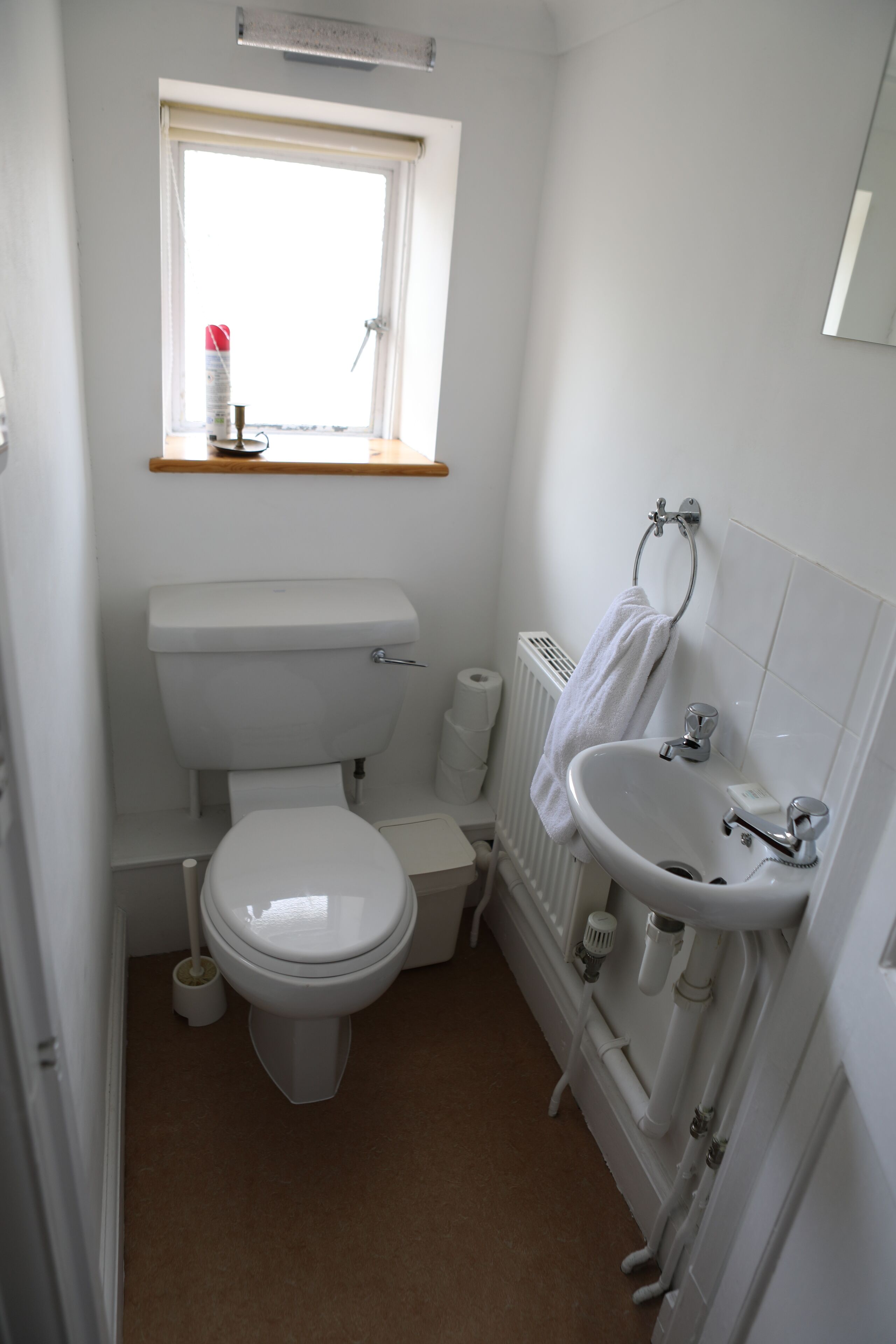 A small, compact bathroom with a toilet, sink, and window.