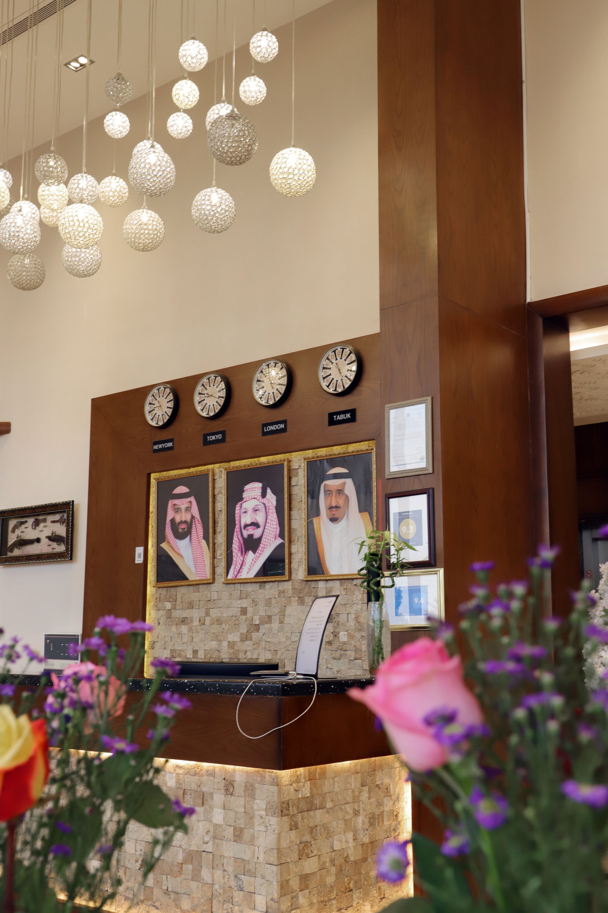 A reception desk with clocks indicating New York, Tokyo, and London times, framed portraits, and a wooden reception area.
