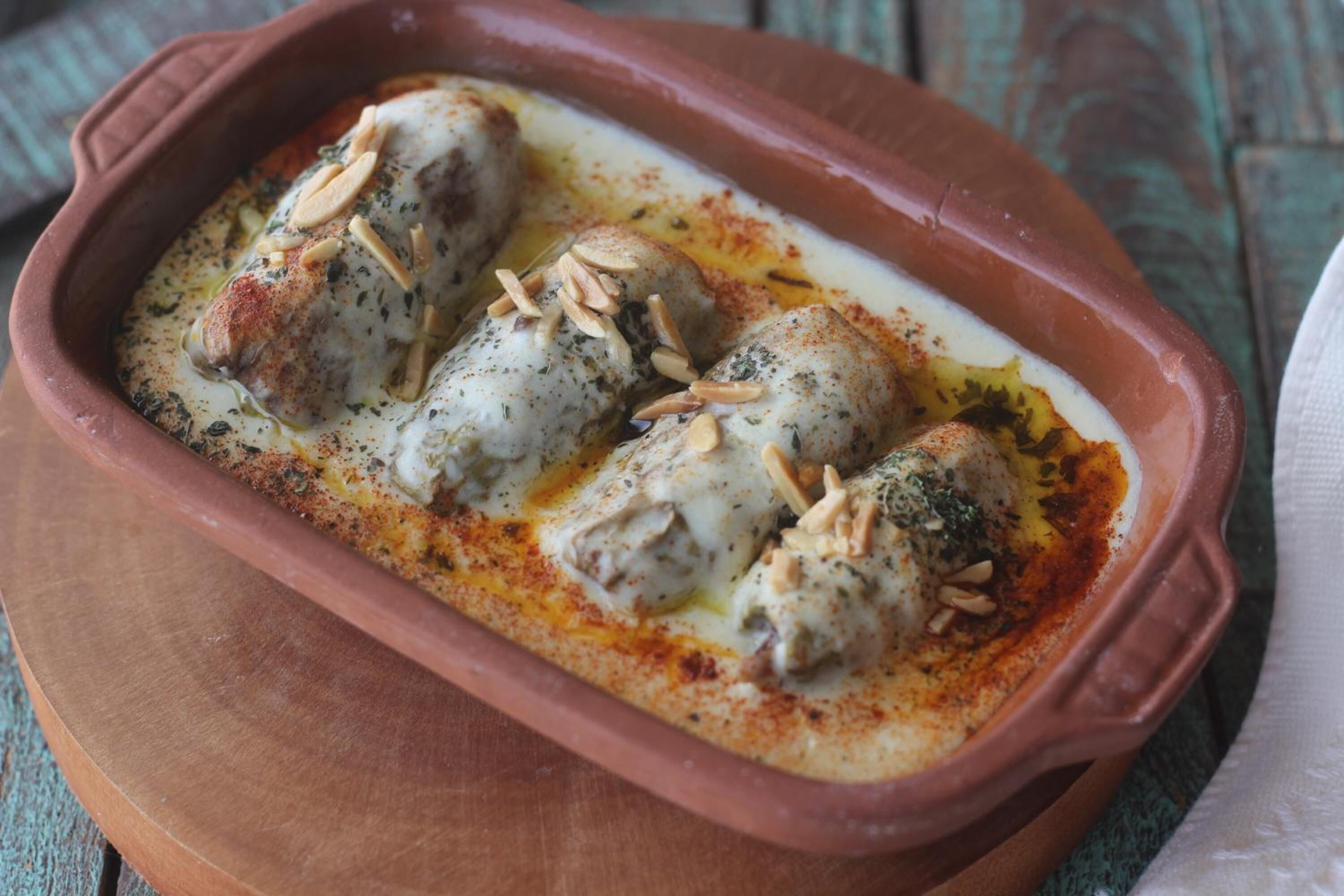 Un plato de terracota con salsa cremosa, adornado con almendras, sobre una superficie de madera.