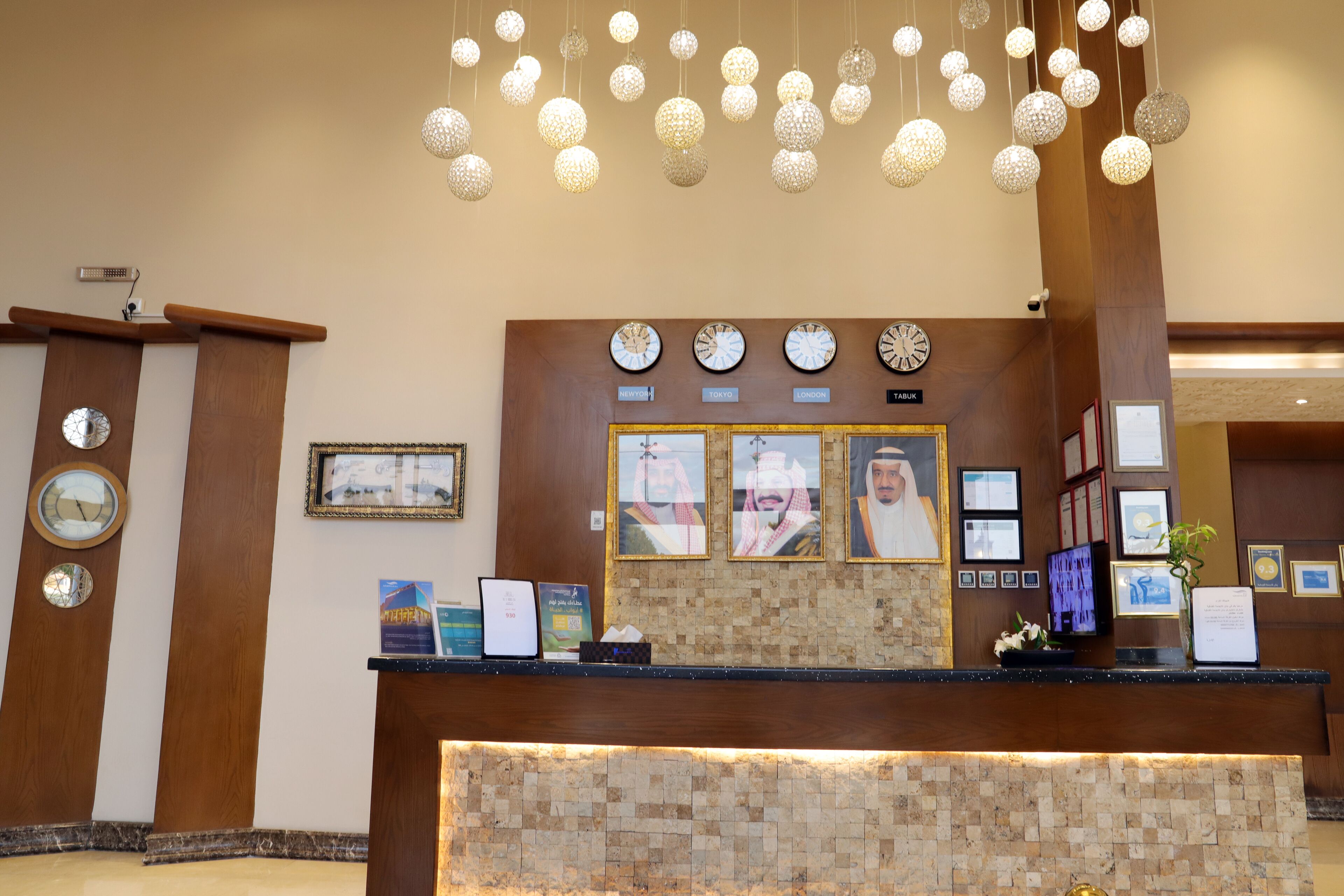 A reception desk with clocks, framed pictures, and a decorative hanging light fixture.