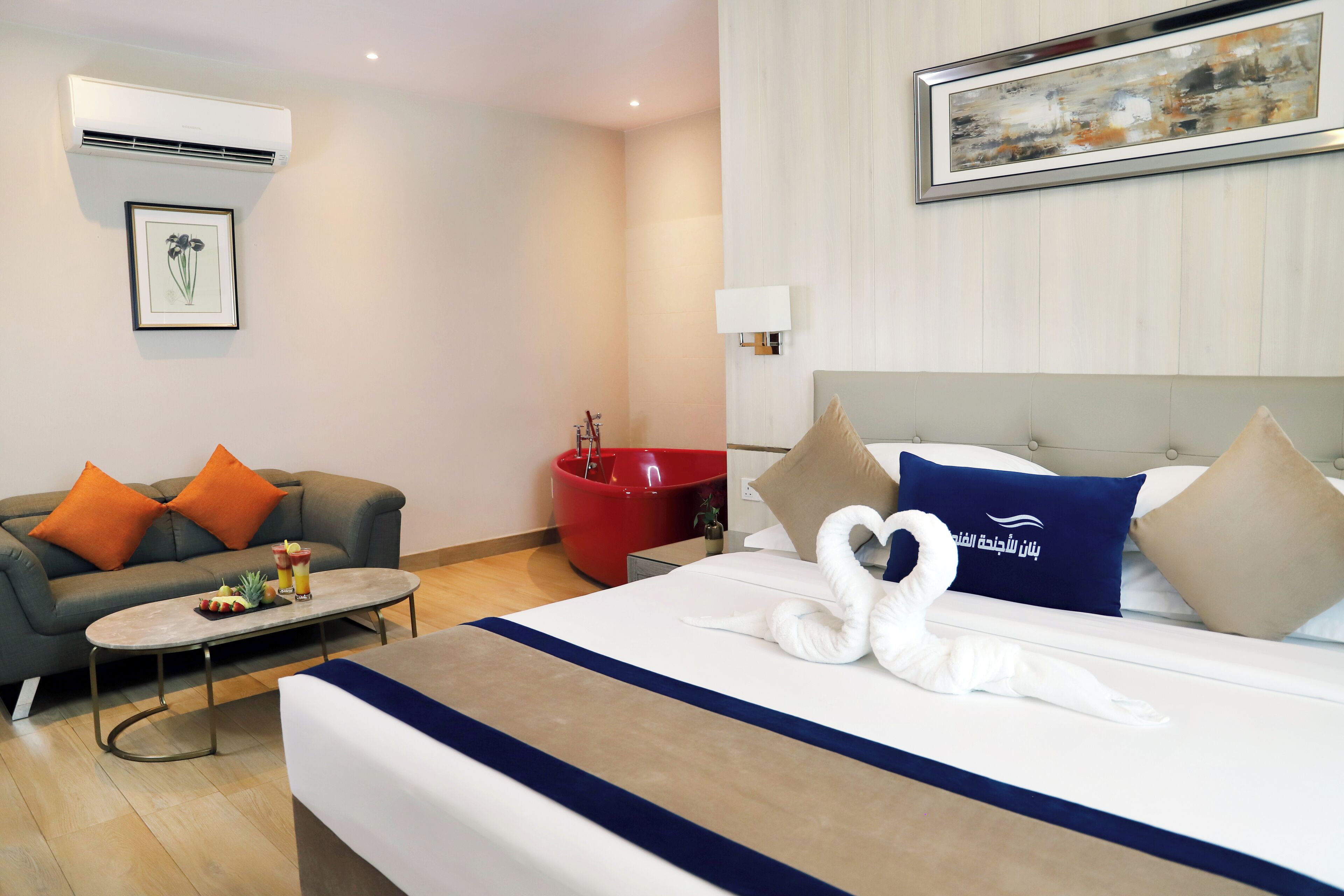 A hotel room with a bed, a sofa, a red bucket, and a framed picture on the wall.