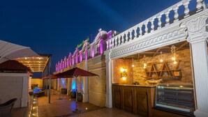 Un área de bar al aire libre con mostrador, columnas decorativas y un letrero que dice 'Barton Lane'.