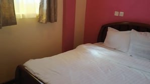 Une pièce avec un lit, des rideaux et un mur orné de motifs à rayures.