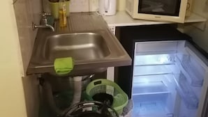 Une cuisine compacte équipée d’un évier, d’un four à micro-ondes, d’un réfrigérateur et d’une cuisinière à gaz.