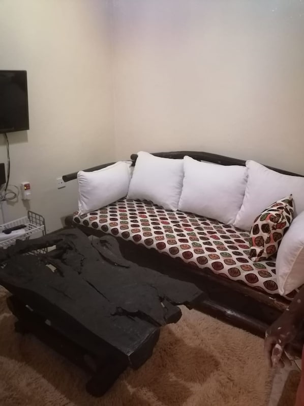 A room with a sofa, a coffee table, and a television mounted on the wall.