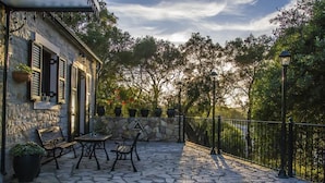 An outdoor patio with stone flooring, a stone wall, and a metal fence. - Su La Strata house  by CorfuEscapes (Paxos)