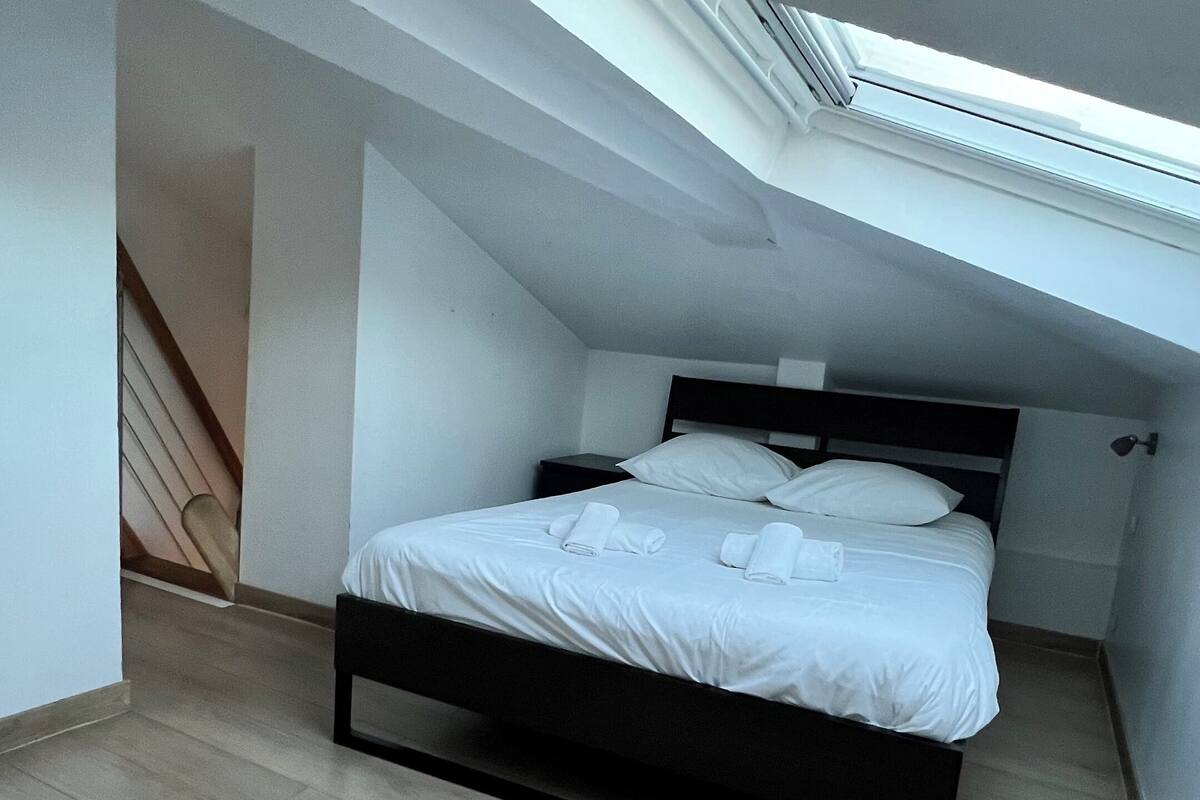 Ein Schlafzimmer mit Oberlicht, einem Bett und einer Treppe.