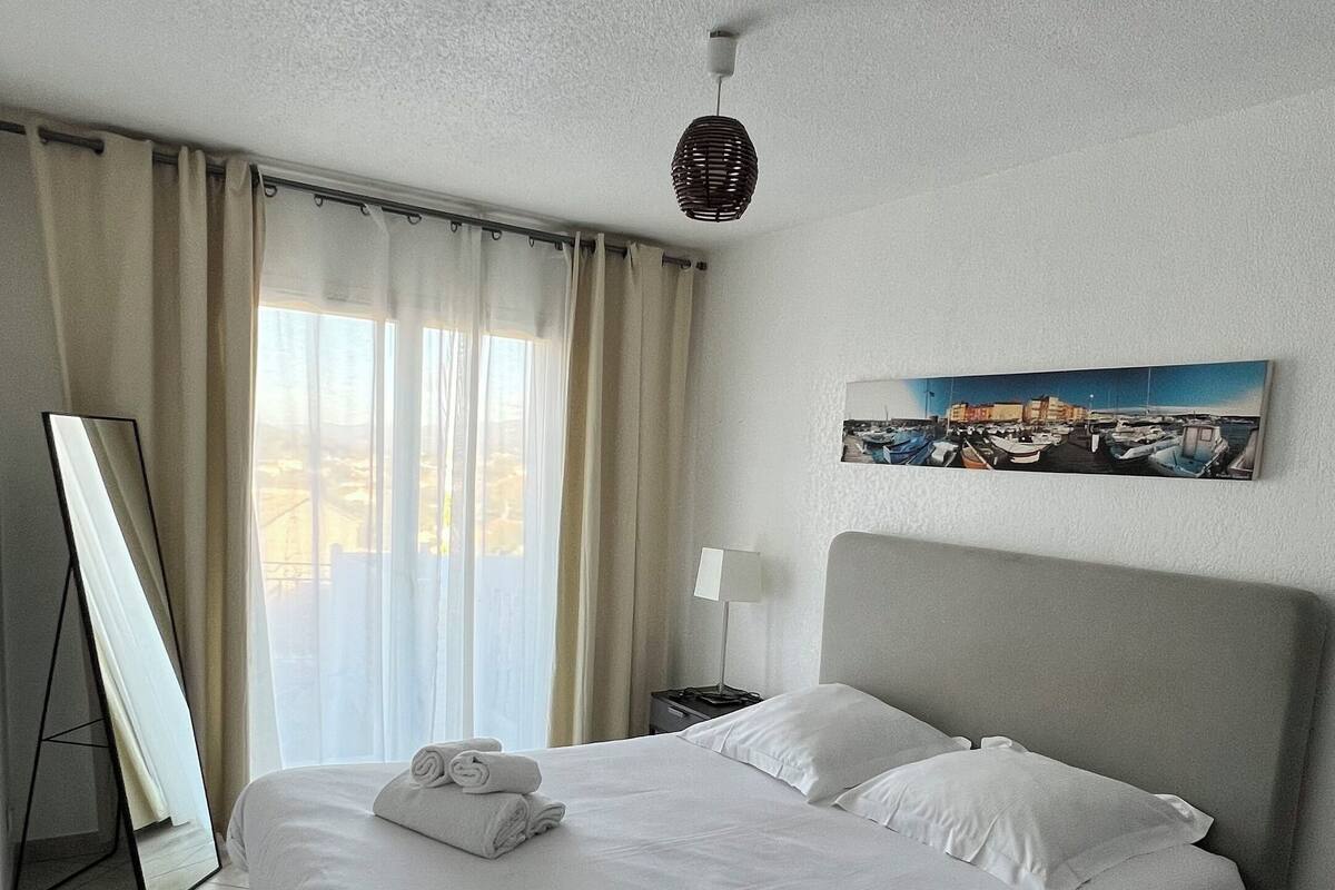 Ein Hotelzimmer mit einem großen Bett, einem Flachbildfernseher, einem Bild an der Wand und Blick ins Freie durch das Fenster.