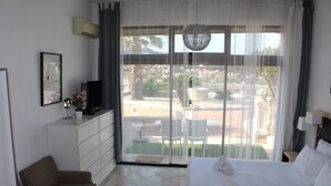 A hotel room with a bed, a sofa, a TV, and a balcony with a view of the city. - Residence les jardins de Natallia (La Seyne-sur-Mer)