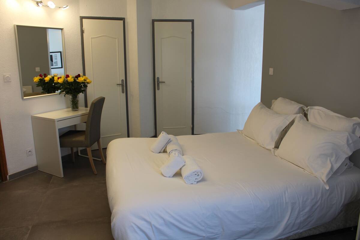 Ein Hotelzimmer mit Bett, Schreibtisch, Stuhl, Spiegel und Tür.