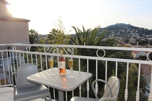 A balcony with a table and chairs, a bottle of wine, and two glasses. - Residence les jardins de Natallia (La Seyne-sur-Mer)