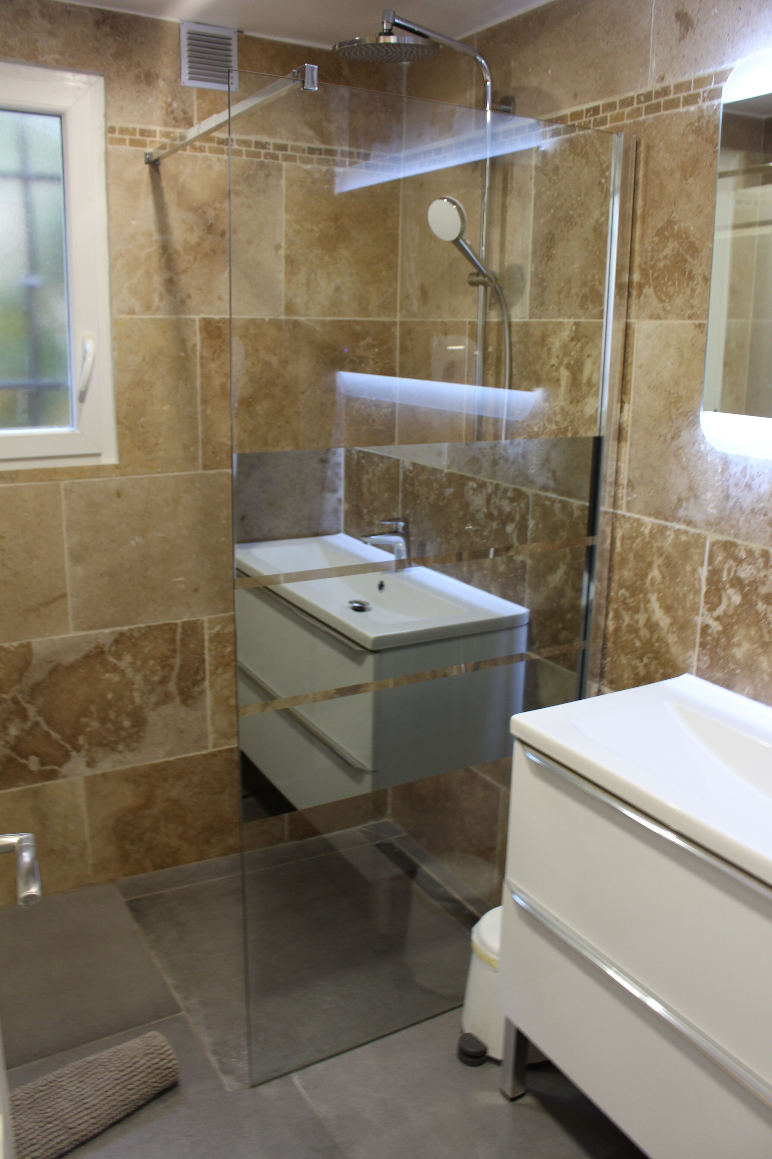 Un baño moderno con ducha envuelta en vidrio, un lavabo blanco y un espejo.