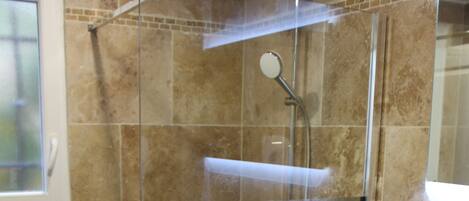Un baño moderno con ducha envuelta en vidrio, un lavabo blanco y un espejo.
