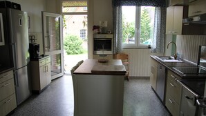 Eine kompakte Küche mit Kühlschrank, Backofen, Spüle und einem Fenster mit Vorhängen.