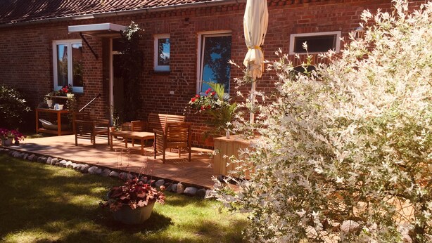 Ein Backsteinhaus mit Terrasse und Sitzgelegenheit im Freien.