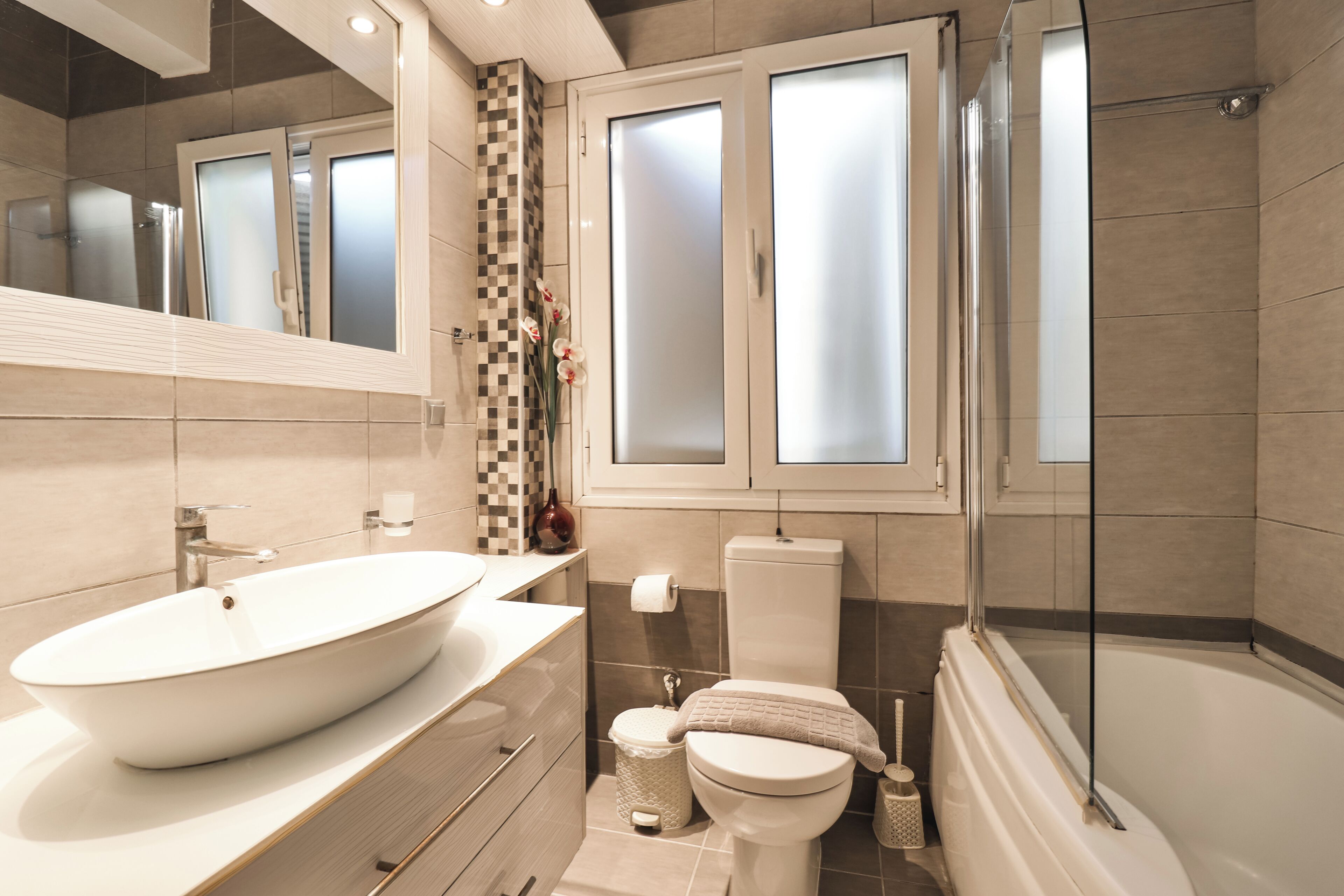 Une salle de bain moderne avec une baignoire sur pieds, un grand miroir et un lavabo avec un receveur apparent.