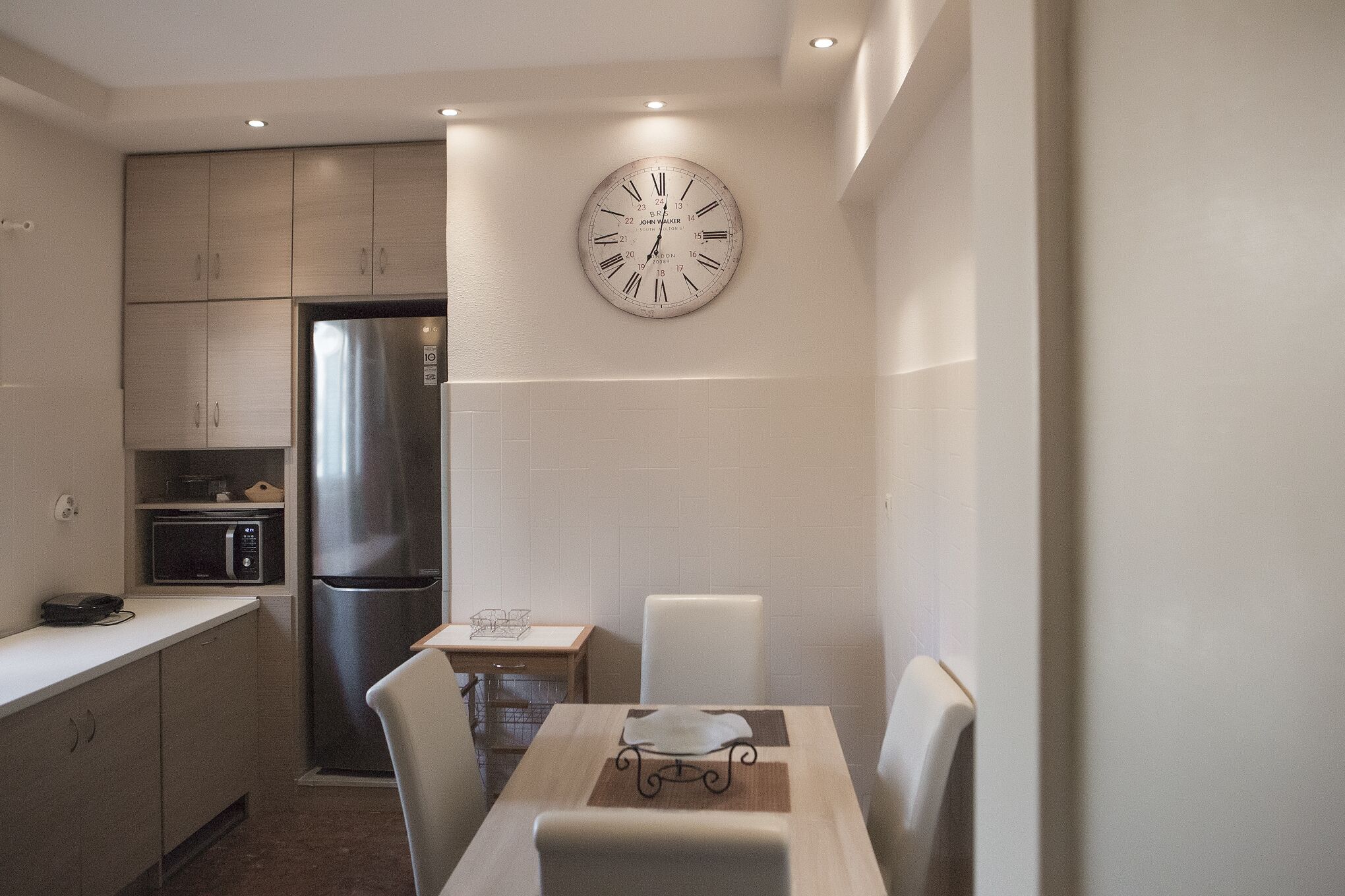 Una cocina compacta con refrigerador de acero inoxidable, un microondas y una mesa de comedor con sillas.