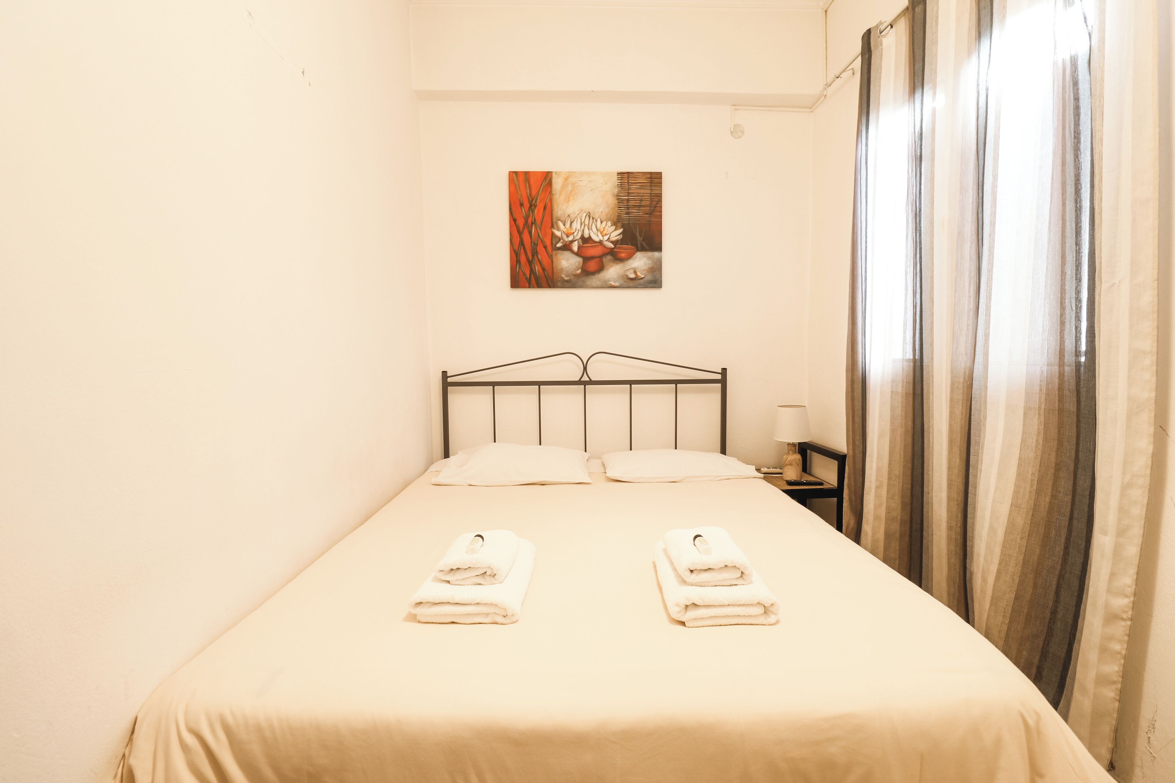 Un lit bien fait avec deux serviettes, une table de chevet avec une lampe et un tableau accroché au mur.