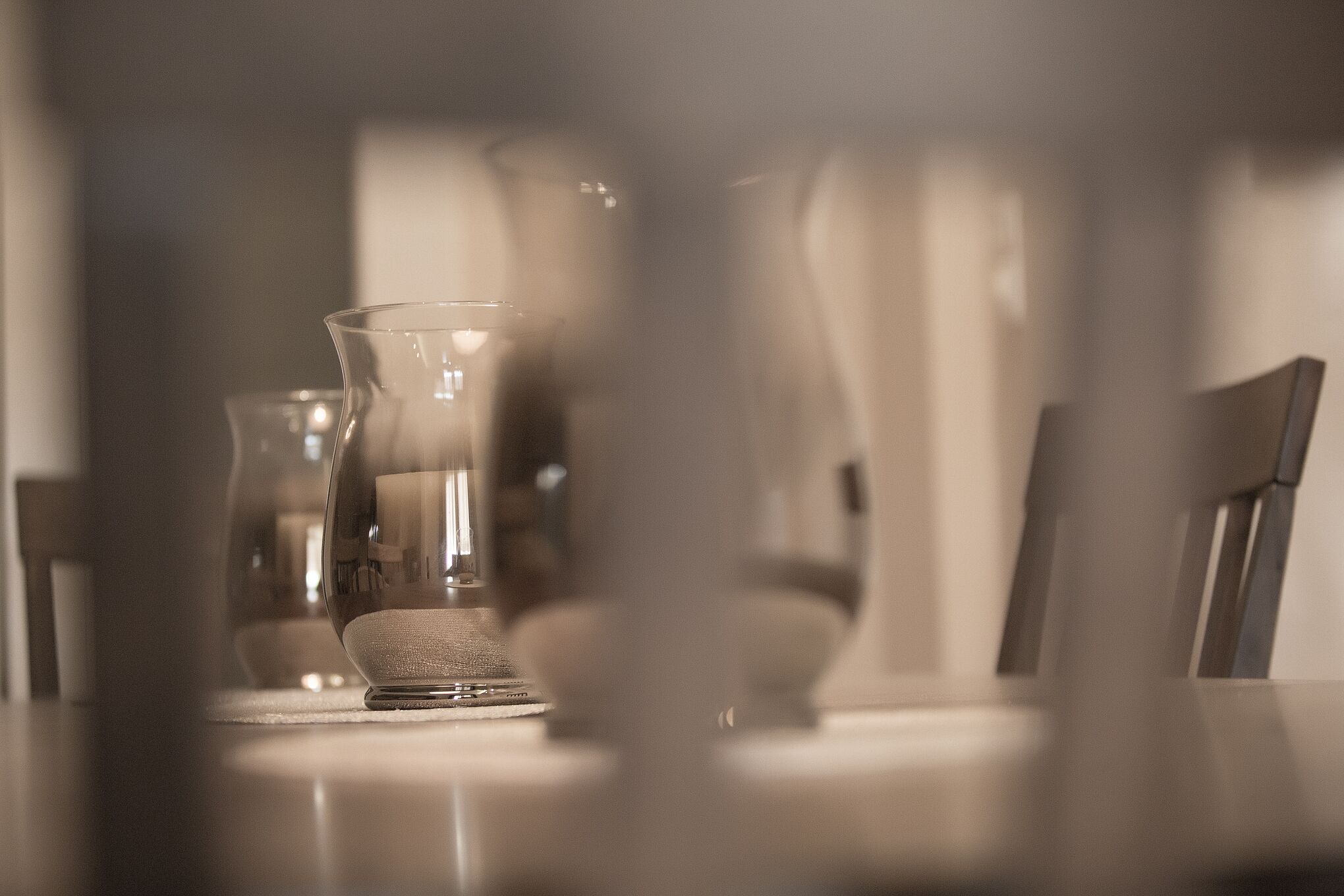 A table with a clear glass vase and a candle holder.