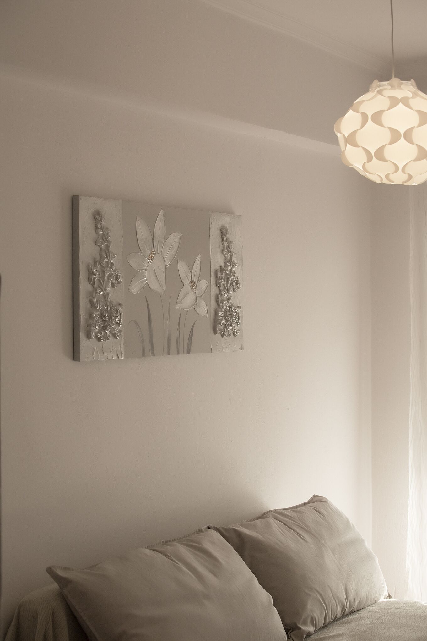 Une chambre à coucher avec un lit, une œuvre d’art accrochée au mur et un luminaire suspendu.