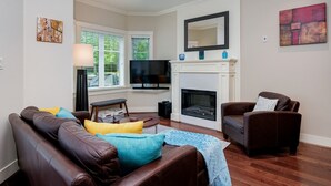 A living room with a fireplace, a television, and a sofa with cushions.